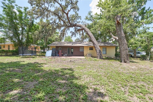 881 Cedar Cir, Tavares, FL 32778 - back of property featuring a trampoline, a patio area, a yard, and central AC
