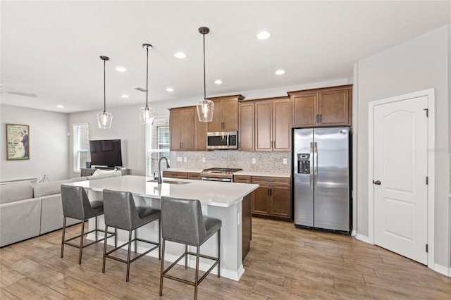 16013 Tollington Aly, Winter Garden, FL 34787 - kitchen featuring stainless steel appliances, a sink, open floor plan, light wood-style flooring, and a kitchen bar