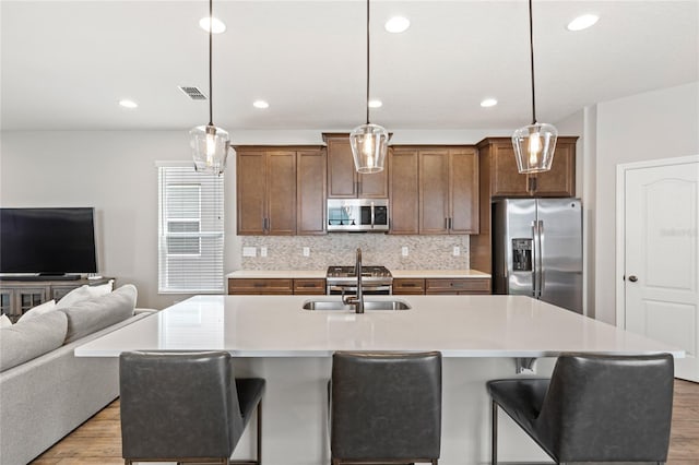16013 Tollington Aly, Winter Garden, FL 34787 - kitchen featuring stainless steel appliances, a sink, open floor plan, light wood-type flooring, and light countertops