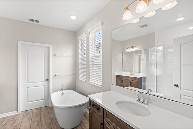 16013 Tollington Aly, Winter Garden, FL 34787 - bathroom with a soaking tub, two vanities, wood finished floors, walk in shower, and baseboards