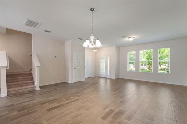 15477 Blackbead St, Winter Garden, FL 34787 - unfurnished living room with a chandelier, stairs, light wood-type flooring, and baseboards