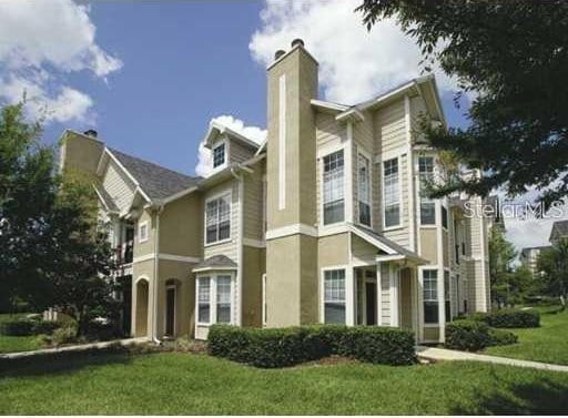 1101 Vintage Village Ln Unit 106, Ocoee, FL 34761 - view of front facade with a chimney and a front yard