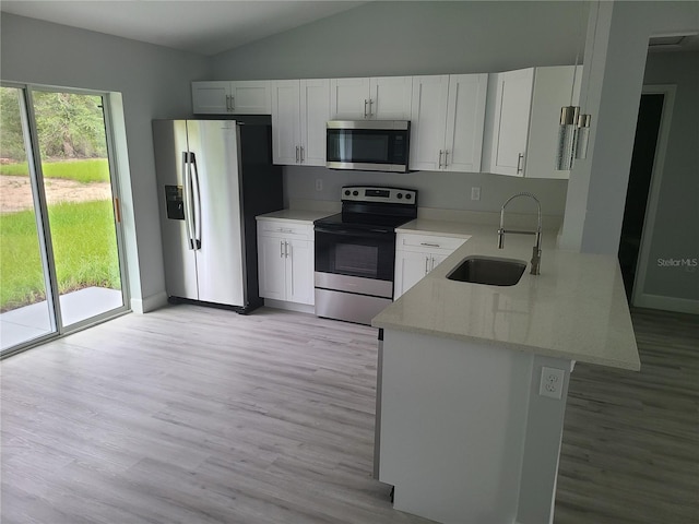 4333 SW 157th Ter, Ocala, FL 34481 - kitchen with appliances with stainless steel finishes, a sink, light wood-style floors, vaulted ceiling, and white cabinetry