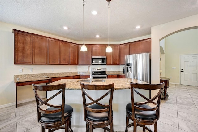 998 Sorrel St NW, Palm Bay, FL 32907 - kitchen with stainless steel appliances, arched walkways, a sink, an island with sink, and a kitchen bar
