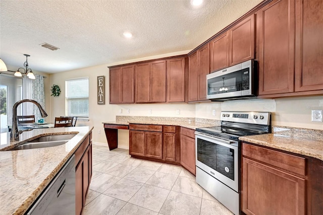 998 Sorrel St NW, Palm Bay, FL 32907 - kitchen featuring stainless steel appliances, a sink, a textured ceiling, light stone countertops, and decorative light fixtures