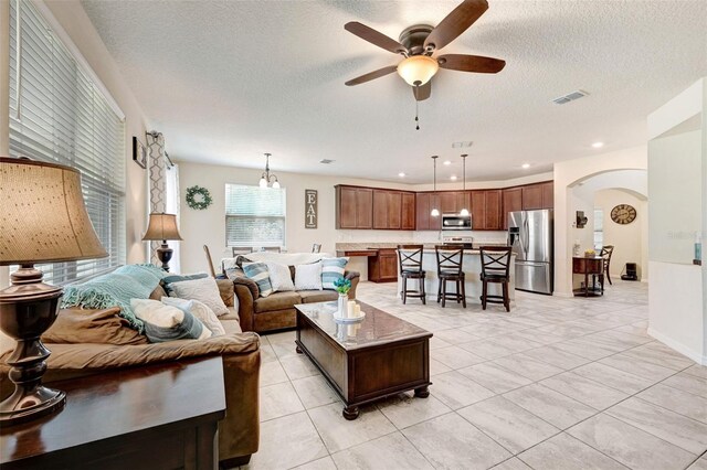 998 Sorrel St NW, Palm Bay, FL 32907 - living room featuring ceiling fan, arched walkways, a textured ceiling, and light tile patterned floors