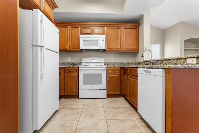 1101 Vintage Village Ln Unit 101, Ocoee, FL 34761 - kitchen featuring white appliances, brown cabinets, light stone counters, light tile patterned floors, and a peninsula