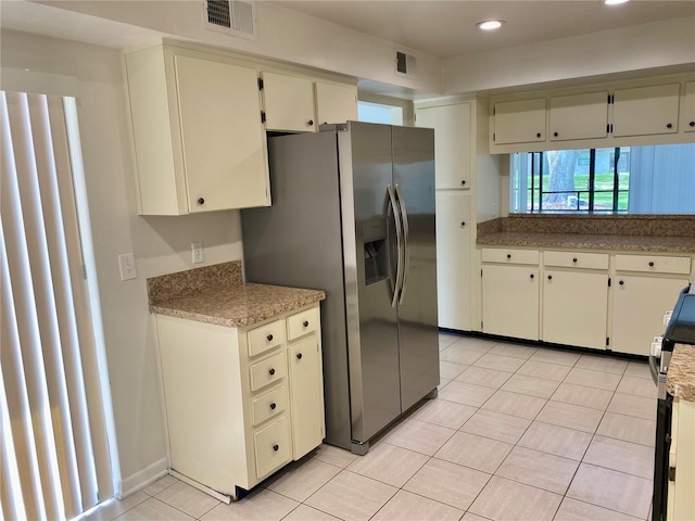 1110 Woodbine St, Fern Park, FL 32730 - kitchen with stainless steel fridge, light tile patterned floors, recessed lighting, cream cabinets, and light countertops