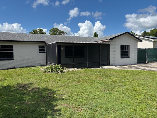 2085 San Jose Blvd, Orlando, FL 32808 - back of house featuring a sunroom, brick siding, and a lawn
