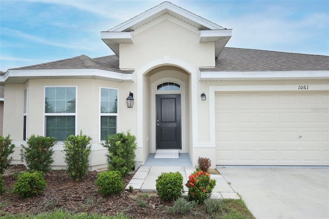 1061 Citrus Landings Blvd, Davenport, FL 33837 - entrance to property featuring a shingled roof, stucco siding, and concrete driveway