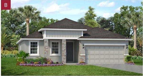 2292 Sirena Ln, Mount Dora, FL 32757 - view of front of house with stone siding, a garage, a front yard, driveway, and a shingled roof
