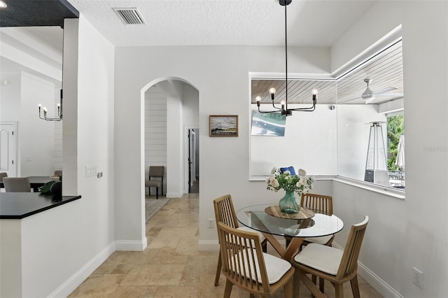 2908 Lee Shore Loop, Orlando, FL 32820 - dining space featuring a chandelier, arched walkways, baseboards, and light stone finish flooring