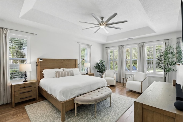 2908 Lee Shore Loop, Orlando, FL 32820 - bedroom featuring a tray ceiling, wood finished floors, a textured ceiling, and a ceiling fan