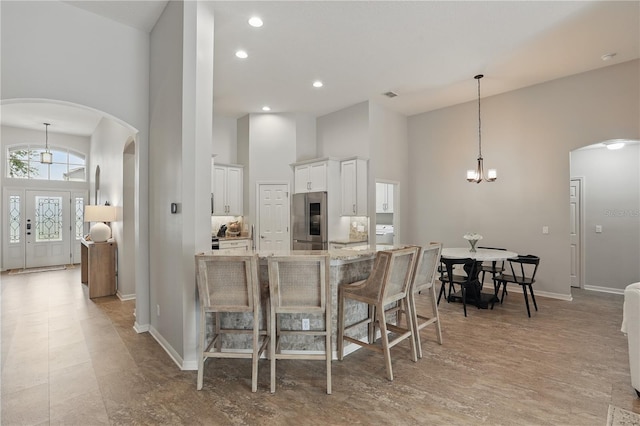 405 Courtlea Park Dr, Winter Garden, FL 34787 - kitchen with arched walkways, stainless steel refrigerator, a high ceiling, a chandelier, and white cabinetry