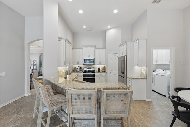 405 Courtlea Park Dr, Winter Garden, FL 34787 - kitchen featuring appliances with stainless steel finishes, washer and clothes dryer, a sink, a towering ceiling, and arched walkways