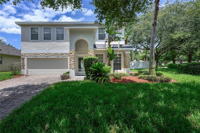 809 Kazaros Cir, Ocoee, FL 34761 - view of front of home with stone siding, an attached garage, decorative driveway, and stucco siding