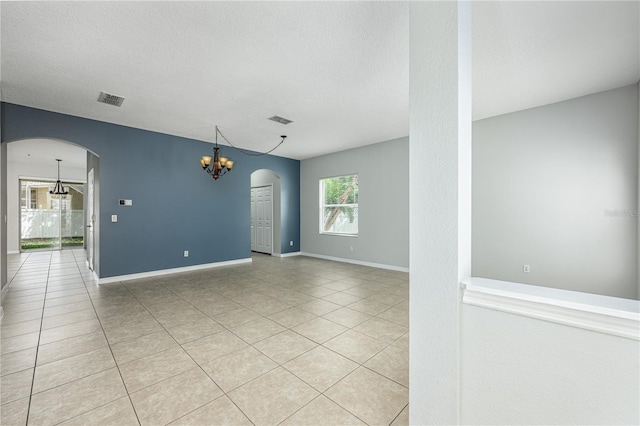 809 Kazaros Cir, Ocoee, FL 34761 - empty room with a chandelier, arched walkways, light tile patterned flooring, baseboards, and a textured ceiling