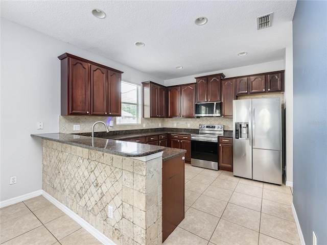809 Kazaros Cir, Ocoee, FL 34761 - kitchen with stainless steel appliances, a peninsula, tasteful backsplash, light tile patterned floors, and a textured ceiling