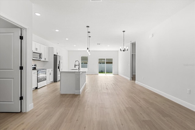14915 SW 39th Cir, Ocala, FL 34473 - kitchen with appliances with stainless steel finishes, white cabinets, light wood-type flooring, open floor plan, and an island with sink