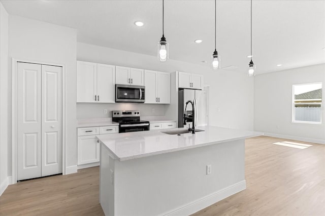 14915 SW 39th Cir, Ocala, FL 34473 - kitchen with stainless steel appliances, a sink, white cabinets, light wood-style floors, and a kitchen island with sink