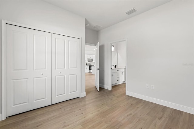 14915 SW 39th Cir, Ocala, FL 34473 - unfurnished bedroom with light wood-style flooring, baseboards, a closet, and ensuite bathroom