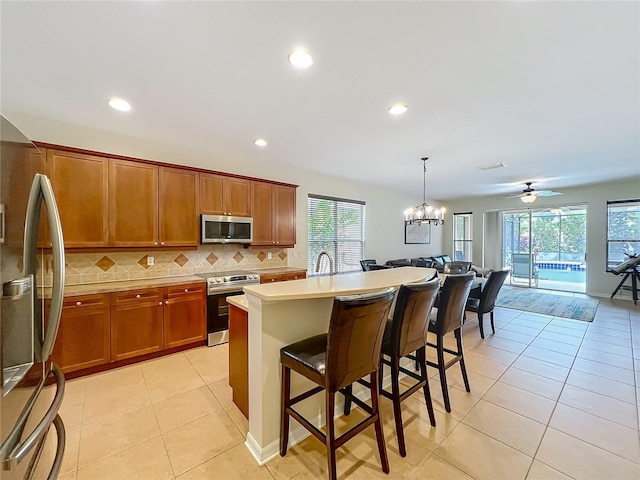 12641 Arley Dr, Windermere, FL 34786 - kitchen with appliances with stainless steel finishes, tasteful backsplash, a kitchen bar, light tile patterned floors, and brown cabinetry