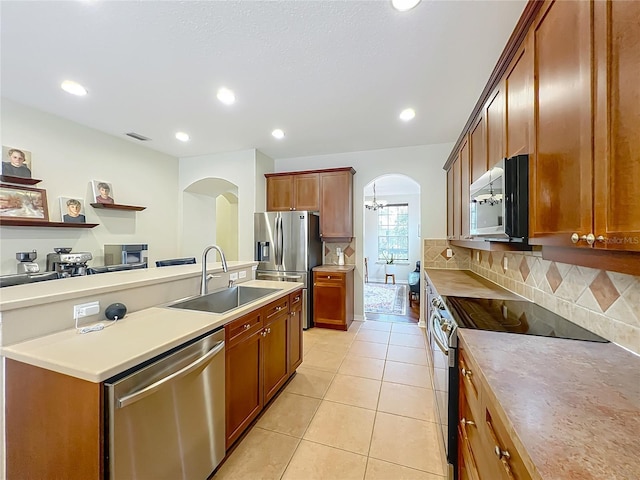 12641 Arley Dr, Windermere, FL 34786 - kitchen featuring appliances with stainless steel finishes, arched walkways, a sink, decorative backsplash, and light tile patterned flooring