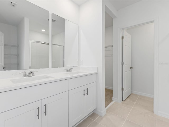 1345 Griffon Ave, Lake Alfred, FL 33850 - bathroom featuring a spacious closet, double vanity, a shower stall, tile patterned flooring, and baseboards