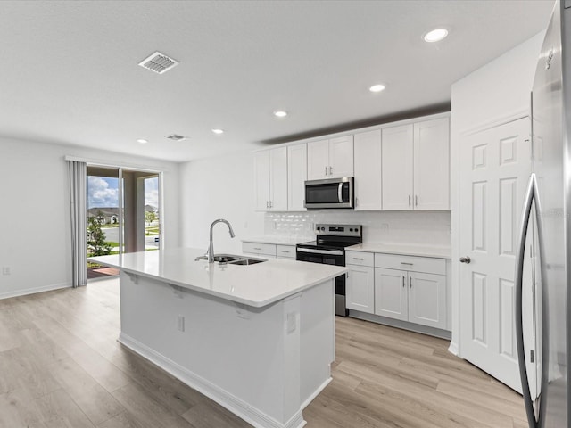 1345 Griffon Ave, Lake Alfred, FL 33850 - kitchen with a sink, appliances with stainless steel finishes, light wood-style floors, white cabinetry, and a kitchen island with sink