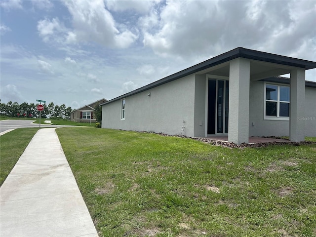 1345 Griffon Ave, Lake Alfred, FL 33850 - view of side of property with stucco siding and a yard