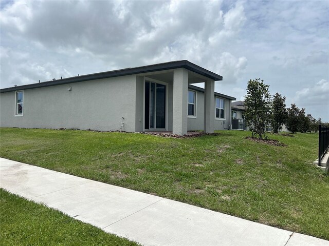 1345 Griffon Ave, Lake Alfred, FL 33850 - rear view of house with stucco siding, central AC unit, and a yard