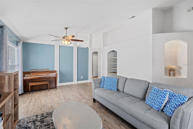 2913 Wilshire Rd, Clermont, FL 34714 - living area featuring wood finished floors, a ceiling fan, built in features, and arched walkways