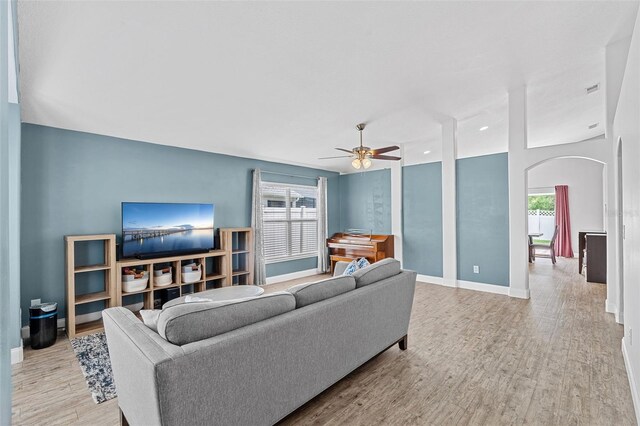 2913 Wilshire Rd, Clermont, FL 34714 - living area with arched walkways, wood finished floors, ceiling fan, and plenty of natural light