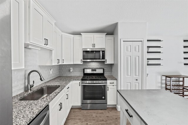 2913 Wilshire Rd, Clermont, FL 34714 - kitchen with stainless steel appliances, white cabinets, backsplash, light wood-style floors, and a textured ceiling