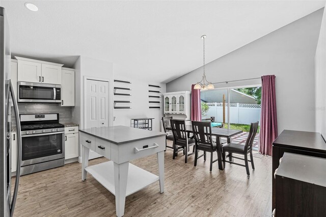 2913 Wilshire Rd, Clermont, FL 34714 - kitchen featuring appliances with stainless steel finishes, a chandelier, light wood finished floors, white cabinetry, and decorative backsplash
