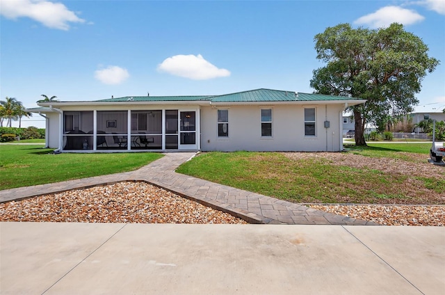 24277 Treasure Island Blvd, Punta Gorda, FL 33955 - rear view of house featuring a sunroom, a lawn, stucco siding, and a metal roof