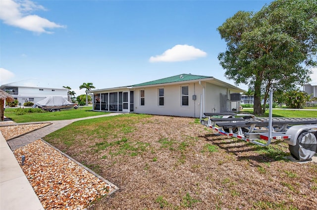 24277 Treasure Island Blvd, Punta Gorda, FL 33955 - view of front of house featuring a sunroom, a metal roof, a front lawn, and stucco siding