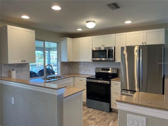 24277 Treasure Island Blvd, Punta Gorda, FL 33955 - kitchen with appliances with stainless steel finishes, light stone counters, a peninsula, light wood finished floors, and recessed lighting