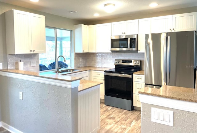 24277 Treasure Island Blvd, Punta Gorda, FL 33955 - kitchen with stainless steel appliances, light stone counters, light wood-type flooring, white cabinets, and recessed lighting
