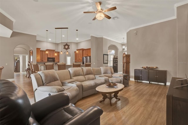 2313 Pesaro Cir, Ocoee, FL 34761 - living room with arched walkways, light wood-style flooring, a ceiling fan, crown molding, and baseboards
