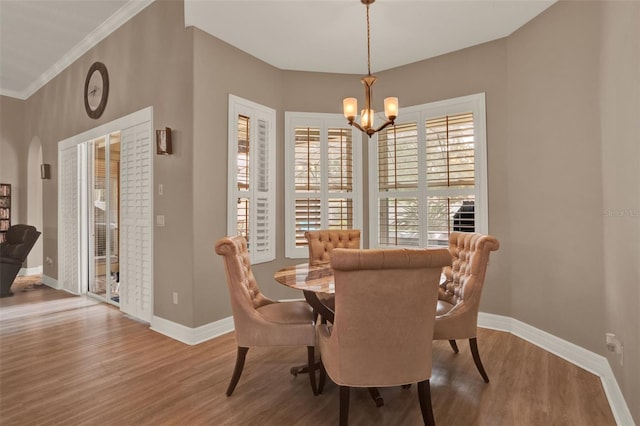 2313 Pesaro Cir, Ocoee, FL 34761 - dining area featuring a chandelier, wood finished floors, baseboards, crown molding, and arched walkways