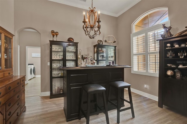 2313 Pesaro Cir, Ocoee, FL 34761 - indoor dry bar featuring washing machine and clothes dryer, arched walkways, light wood-style flooring, baseboards, and crown molding