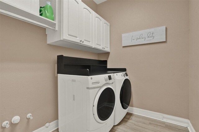 2313 Pesaro Cir, Ocoee, FL 34761 - laundry area with independent washer and dryer, baseboards, light wood-style floors, and cabinet space