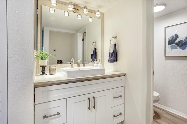 563 Midway Trak Unit K102, Ocala, FL 34472 - bathroom with vanity, toilet, wood finished floors, baseboards, and a textured wall