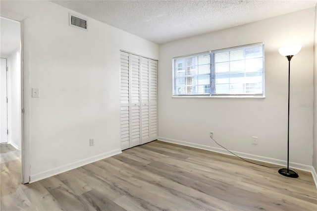 563 Midway Trak Unit K102, Ocala, FL 34472 - unfurnished bedroom featuring wood finished floors, baseboards, a textured ceiling, and a closet