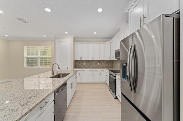 16357 SE 88th Ct, Summerfield, FL 34491 - kitchen featuring stainless steel appliances, a sink, white cabinets, ornamental molding, and light stone countertops