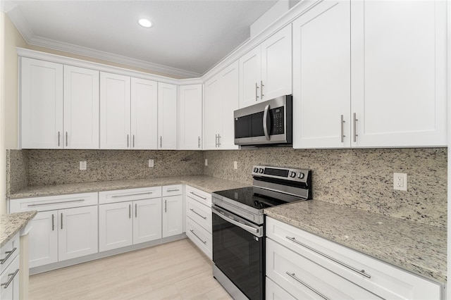 16357 SE 88th Ct, Summerfield, FL 34491 - kitchen with stainless steel appliances, white cabinets, light stone countertops, crown molding, and recessed lighting