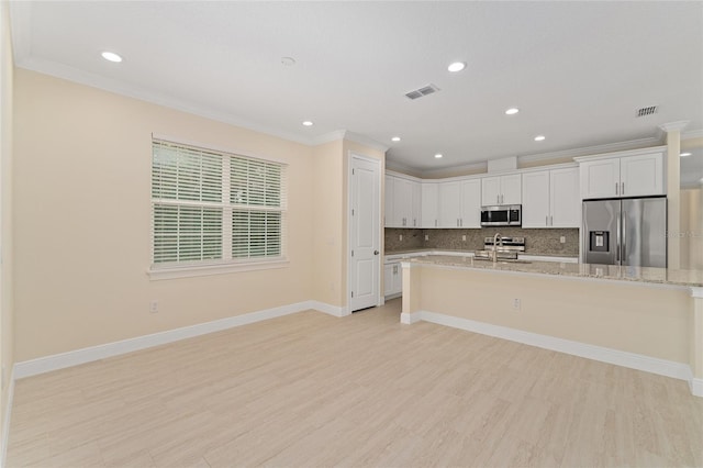 16357 SE 88th Ct, Summerfield, FL 34491 - kitchen with appliances with stainless steel finishes, crown molding, light wood-style flooring, decorative backsplash, and white cabinets