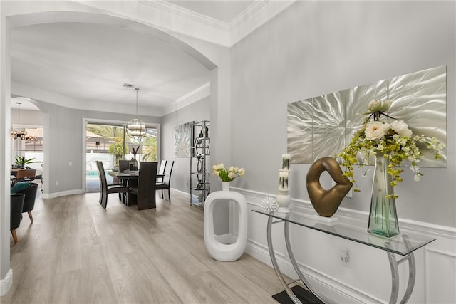 6426 Montclair Bluff Ln, Windermere, FL 34786 - dining area featuring a chandelier, arched walkways, light wood-style floors, crown molding, and baseboards