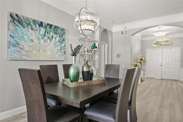 6426 Montclair Bluff Ln, Windermere, FL 34786 - dining room with a chandelier, arched walkways, light wood-style floors, crown molding, and baseboards